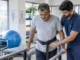 Physiotherapist assisting stroke survivor with walking exercise in rehab clinic
